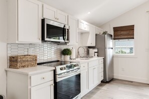 A modern kitchen with white cabinetry, a stainless steel microwave, a built-in oven, and a refrigerator. -  Adorable Upscale cottage in Downtown Fountain Inn.  (Fountain Inn)