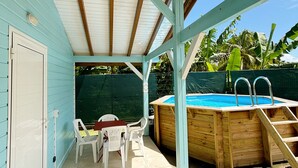 A covered patio area with a pool, a table with chairs, and a door with a 'hello' mat. - Bunghello Village - Private Pool & Spa | Évasion Tropicale (Trois-Rivières)