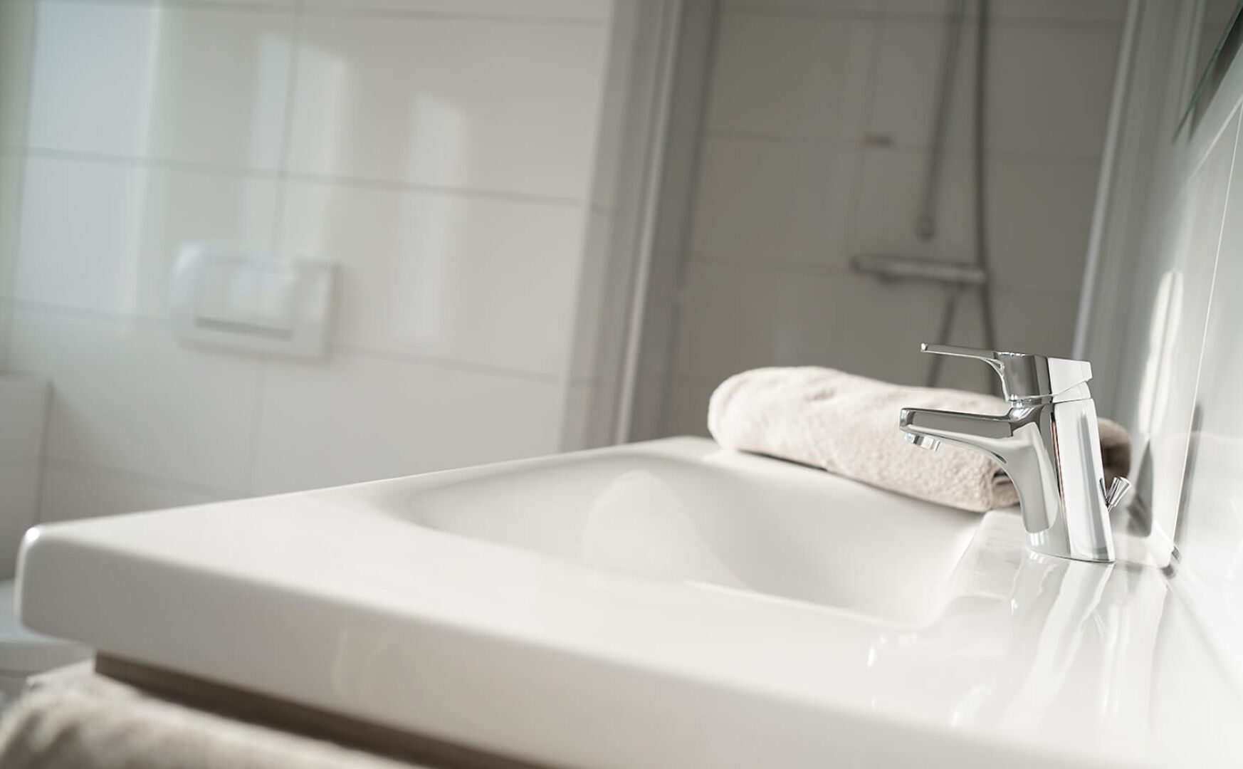 Une salle de bain moderne avec un lavabo blanc, un robinet chromé et une serviette posée sur le comptoir.