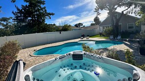 A backyard with two swimming pools, a hot tub, and a fenced area with lounge chairs. - Pool & Hot Tub Home (St. Augustine)