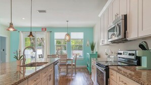 A kitchen with a central island, wooden cabinets, stainless steel appliances, and pendant lighting. - Pool & Hot Tub Home (St. Augustine)