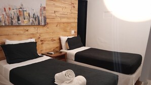 A hotel room with two beds, wooden paneling on the walls, a painting, and a nightstand with a phone and remote control. - Santa Maria Express (Santiago)