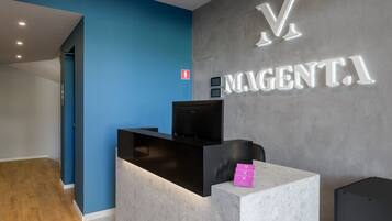 A reception desk with a modern design, a blue wall, and a grey wall with illuminated signage.