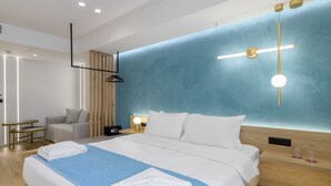 A modern hotel room with a large bed, bedside tables, a desk, and a seating area. - Acropolis Magenta (Athens)