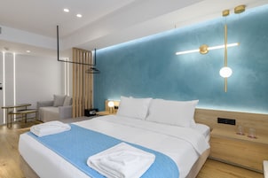 A modern hotel room with a large bed, bedside tables, a desk, and a seating area.
