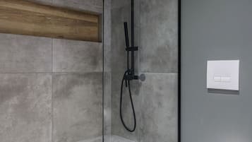 Une salle de bain moderne avec une douche à parois de verre, des toilettes blanches et une étagère en bois.
