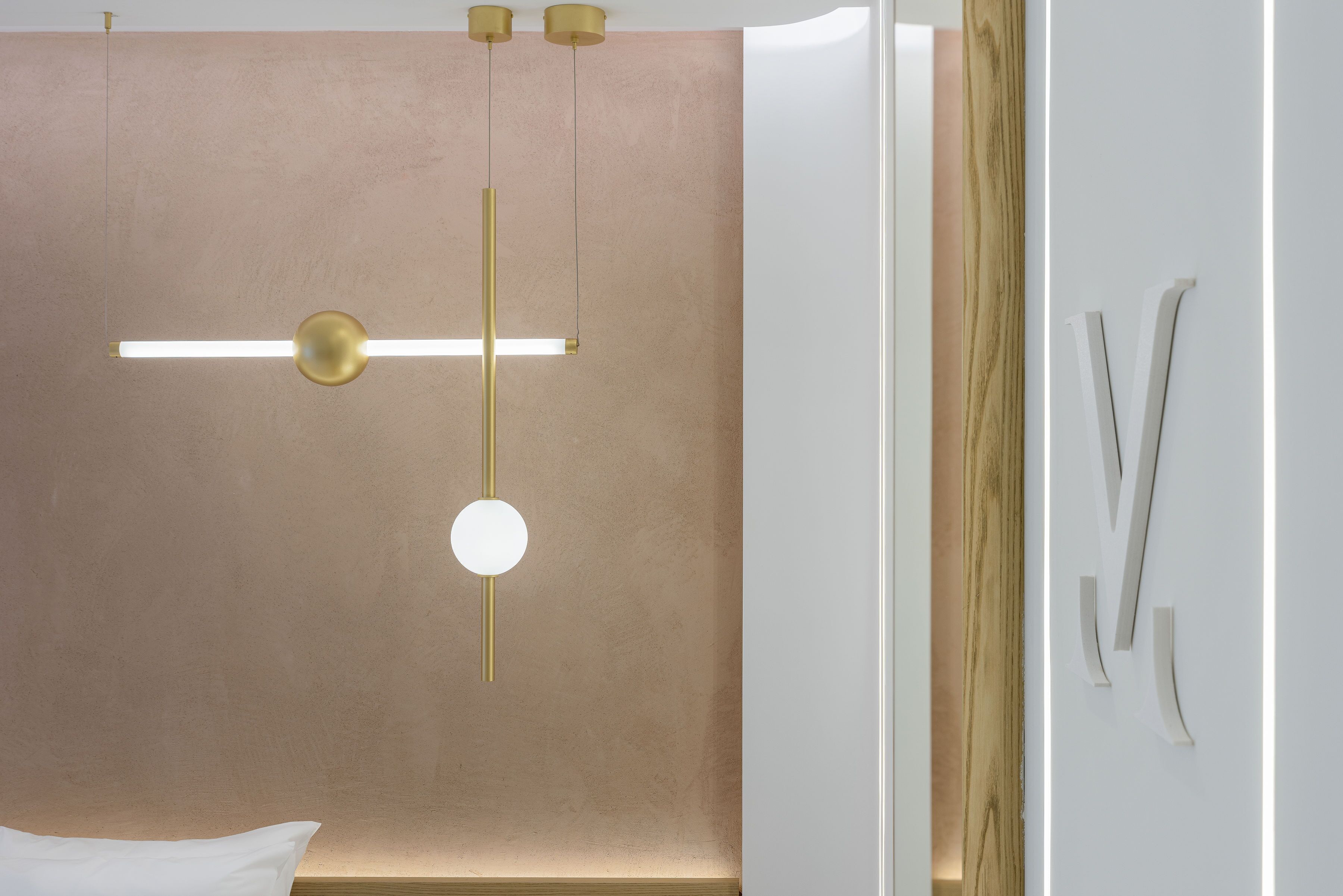 A modern hotel room with a minimalist design, featuring a large bed, a wall-mounted light fixture, and a wooden accent wall.