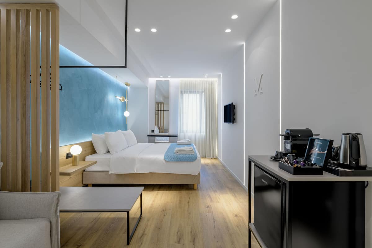 A modern hotel room with a large bed, bedside table, and a desk with a coffee machine.