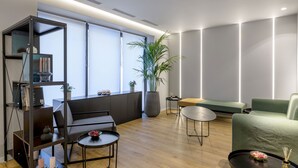 A modern living room with a sofa, coffee table, and bookshelf. - Acropolis Magenta (Athens)