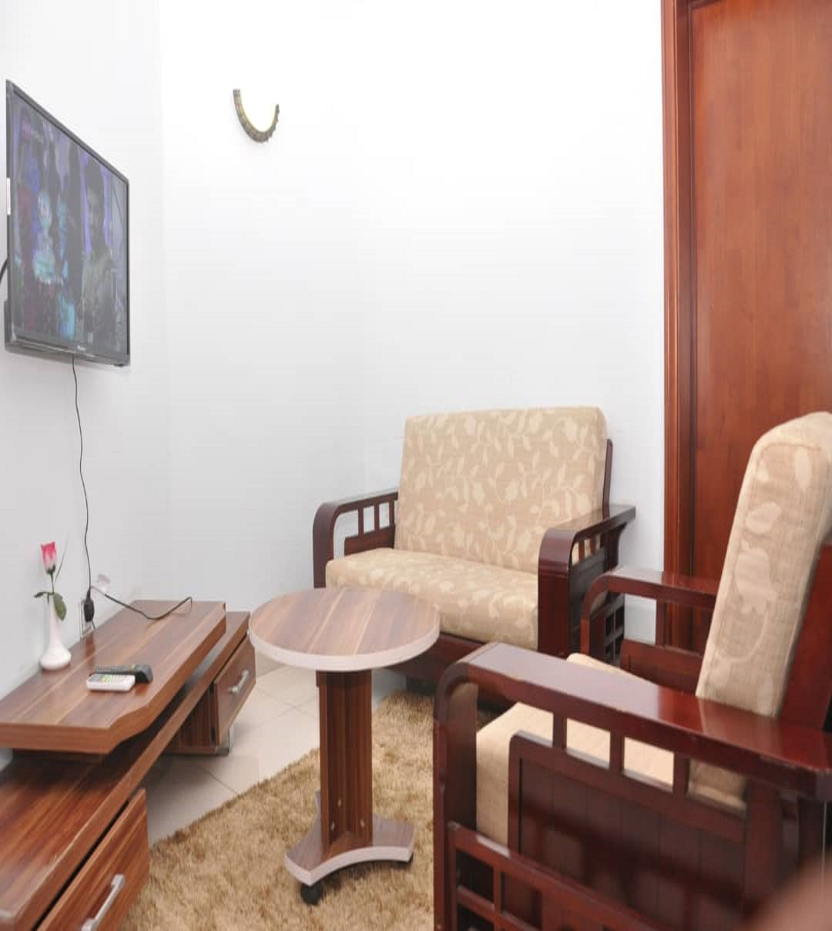 A living room with a sofa, a coffee table, and a TV mounted on the wall.