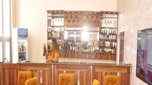 A bar area with wooden paneling, a counter with a bartender, and a selection of bottles. - Fisher Suites and Apartment (Abuja)