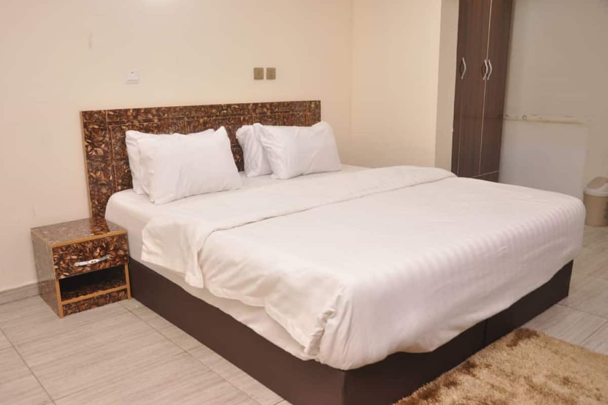 A neatly made bed with a wooden headboard, a small bedside table, and a brown rug.