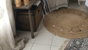 Un salon avec un téléviseur, un fauteuil, une lampe et un tapis tissé.