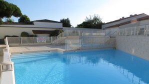 Une piscine entourée d’une clôture blanche et dont les parois sont recouvertes de carreaux.