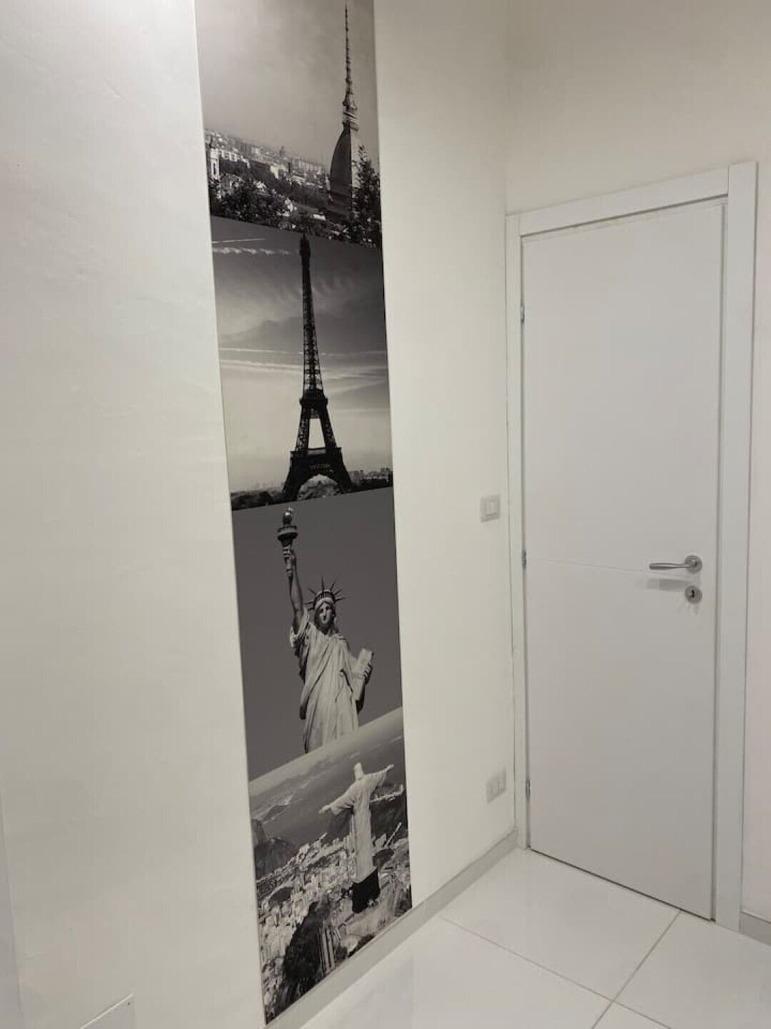 Un corridoio con una porta e un muro decorato con un collage di famosi monumenti.