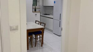 A modern kitchen with white cabinets, a white refrigerator, and a dining table with chairs. - Camilla 's House 2 - “it's cool“. (Torino)