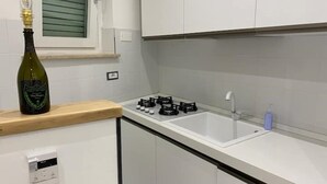 A kitchen with white cabinets, a gas stove, and a wine bottle on the counter. - Camilla 's House 2 - “it's cool“. (Torino)