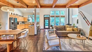 Un vaste espace de vie doté d’un plafond en bois, d’une grande table à manger et d’un canapé.