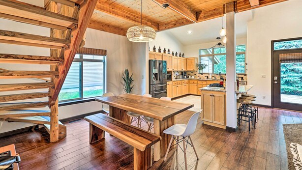Une cuisine spacieuse dotée de meubles en bois, d’un îlot central et d’un coin repas avec une table et des bancs en bois.