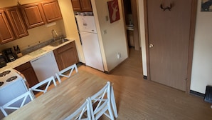 A kitchen with wooden cabinets, a white refrigerator, and a dining area with a white table and chairs. - Windham getaway!  (Windham)