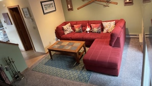 A living room with a red sofa, a wooden coffee table, and a patterned rug. - Windham getaway!  (Windham)