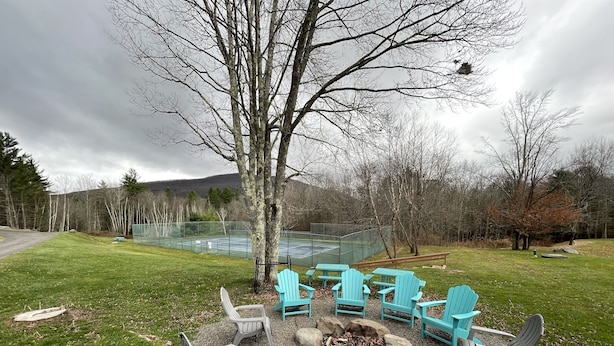 A patio area with outdoor seating and a tennis court in the background. - Windham getaway!  (Windham)