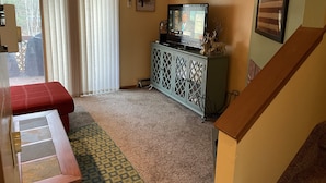 A living room with a television, a cabinet with decorative items, a red bench, and a staircase. - Windham getaway!  (Windham)