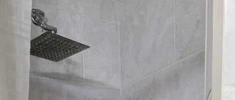 A shower with a handheld showerhead and a wall-mounted control.