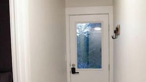 Um corredor estreito com uma porta branca e uma janela.