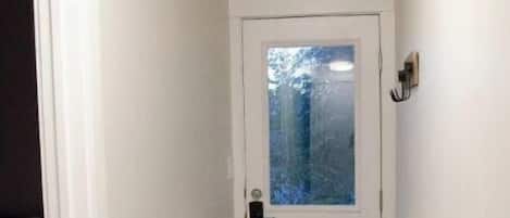 En smal hall med en vit dörr och ett fönster.