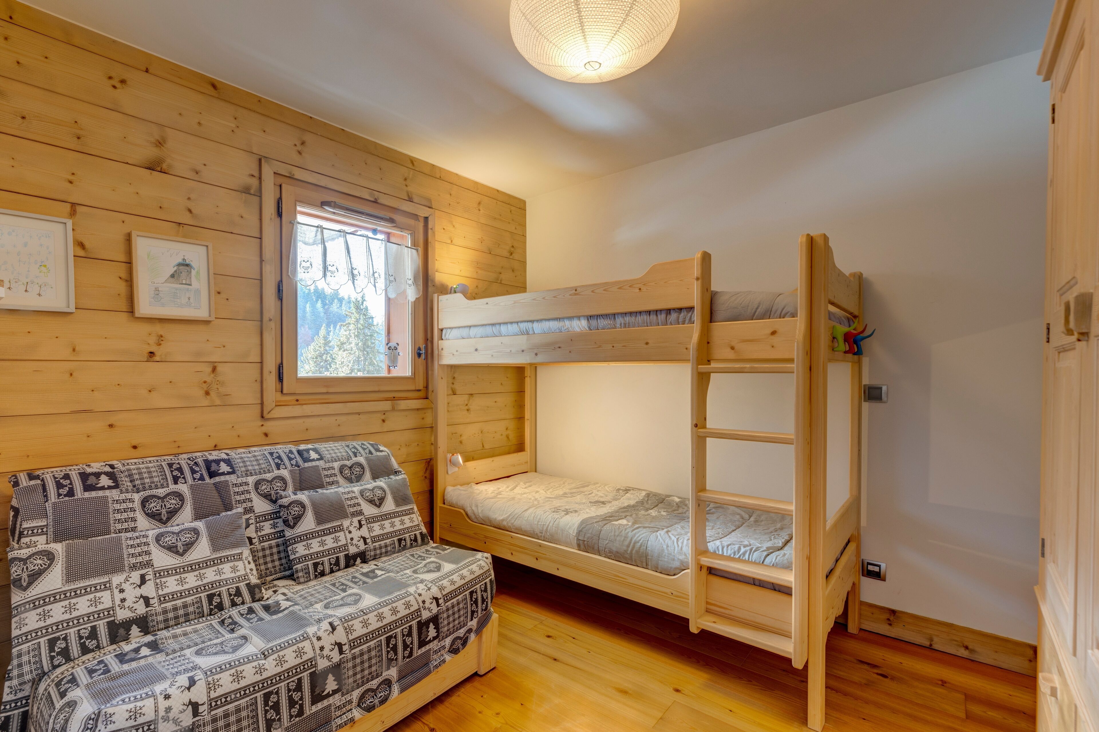 Een houten kamer met een stapelbed, een bank met patroon kussens en ingelijste foto's aan de wand.