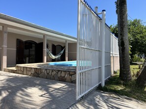 Relax by the pool surrounded by an outdoor space with a hammock and covered porch.