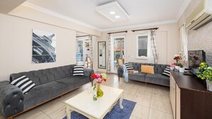 En moderne stue med to grå sofaer, et hvidt sofabord og en blå måtte.