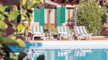 Una piscina al aire libre de temporada, sillones reclinables de piscina