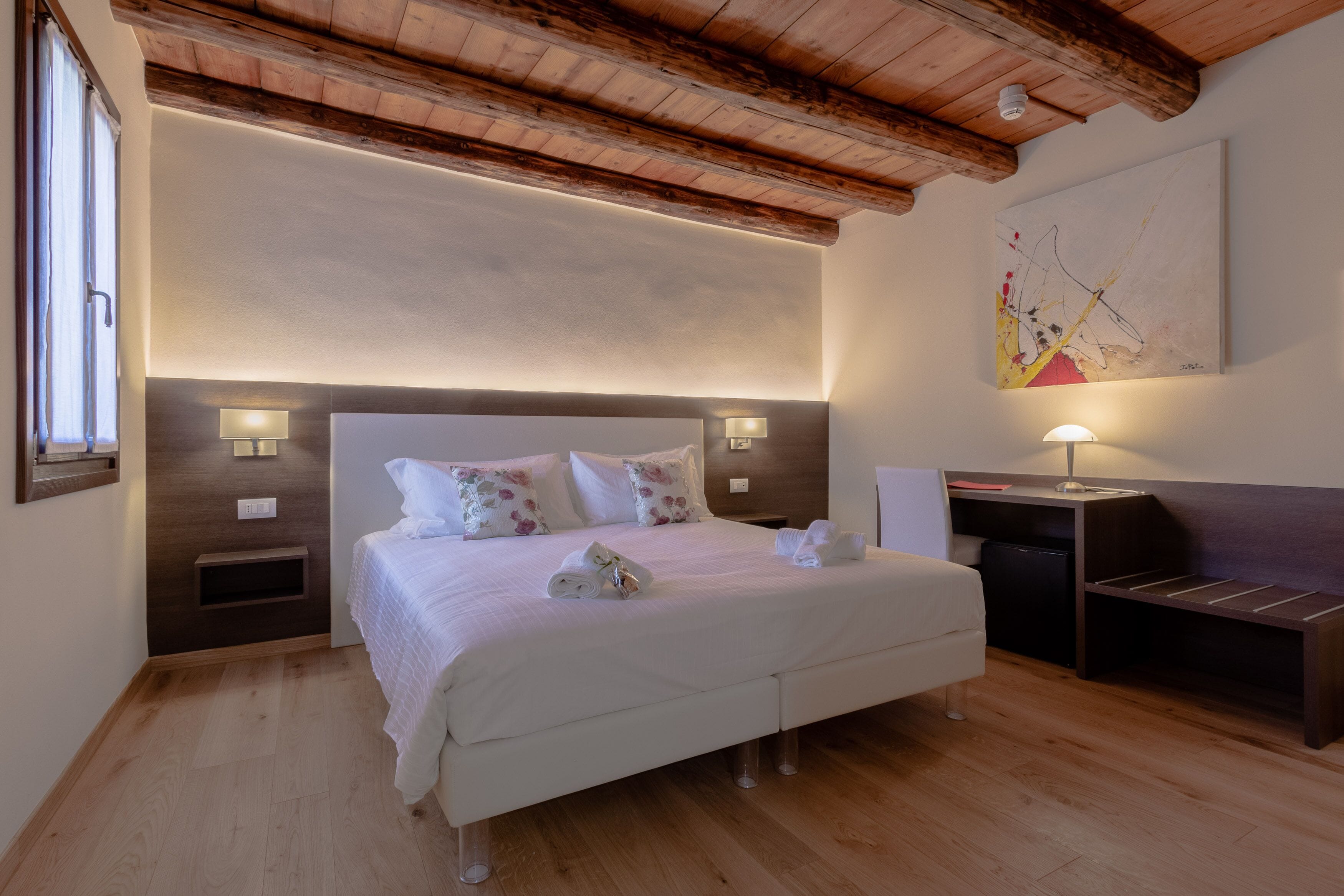 Una camera da letto ordinata con un letto grande, comodini, una scrivania e un quadro appeso al muro.