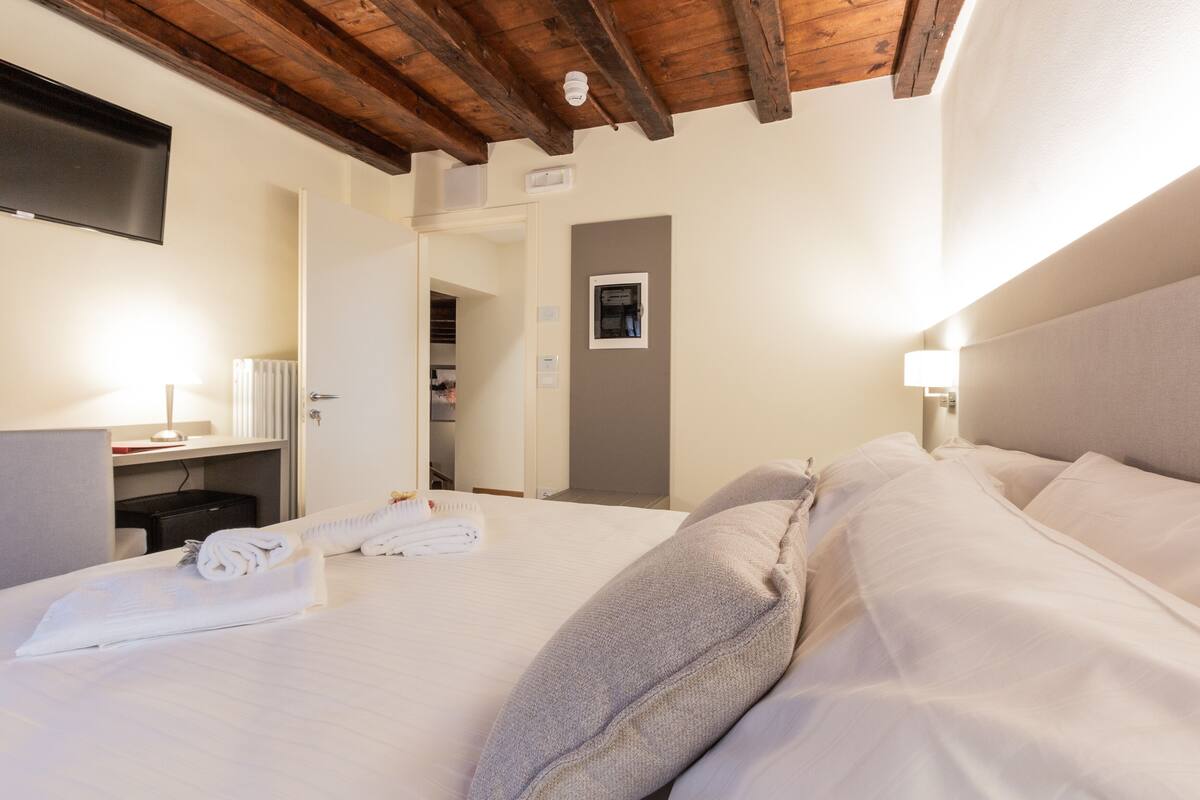 Une chambre d’hôtel comprenant un lit, un bureau, une chaise, un téléviseur et une porte donnant accès à une salle de bain.