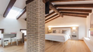 Un dormitorio con chimenea de ladrillo, una cama, mesitas de noche y un escritorio con silla.