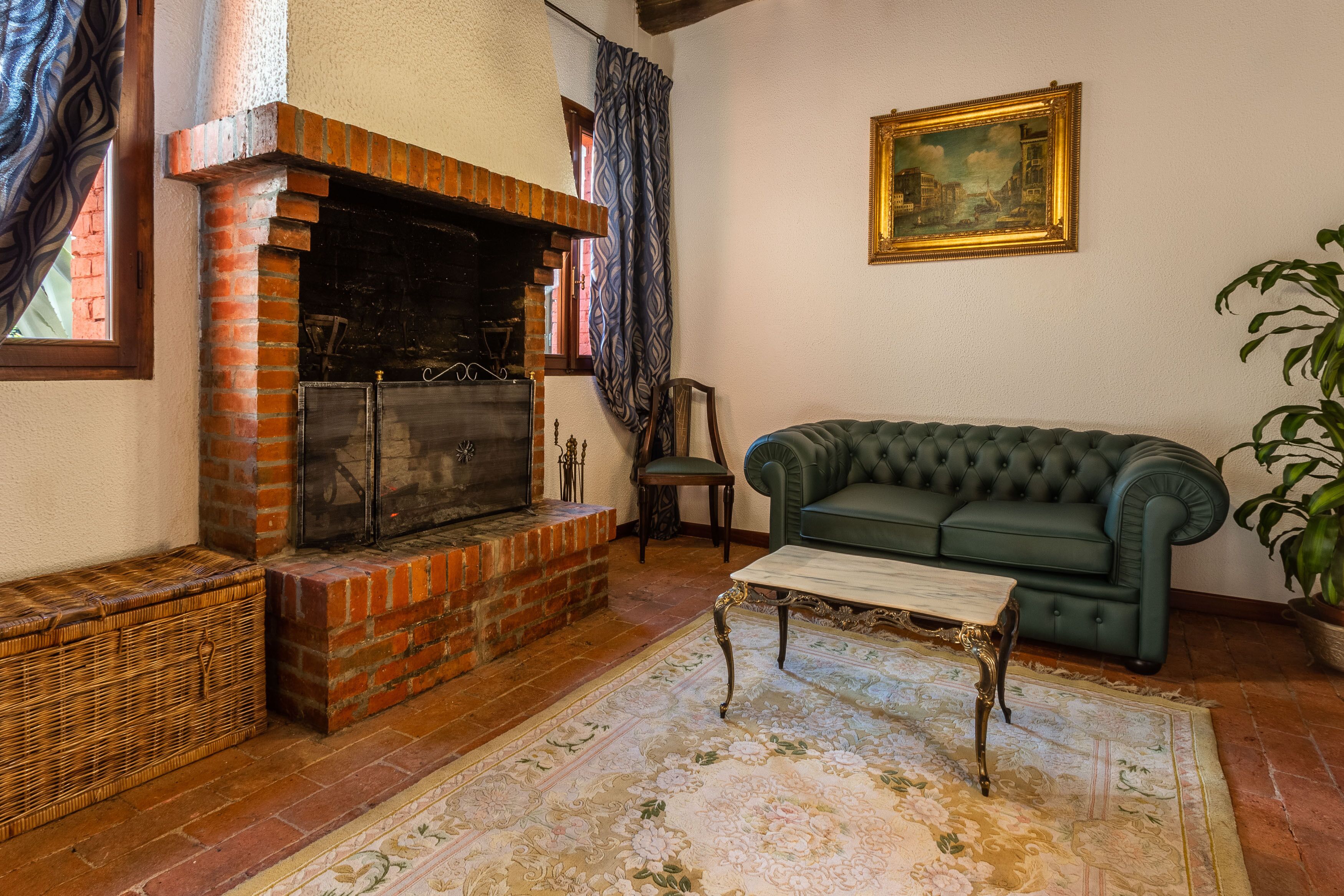 A cozy living room with a brick fireplace, a green sofa, a wooden coffee table, and a patterned rug.