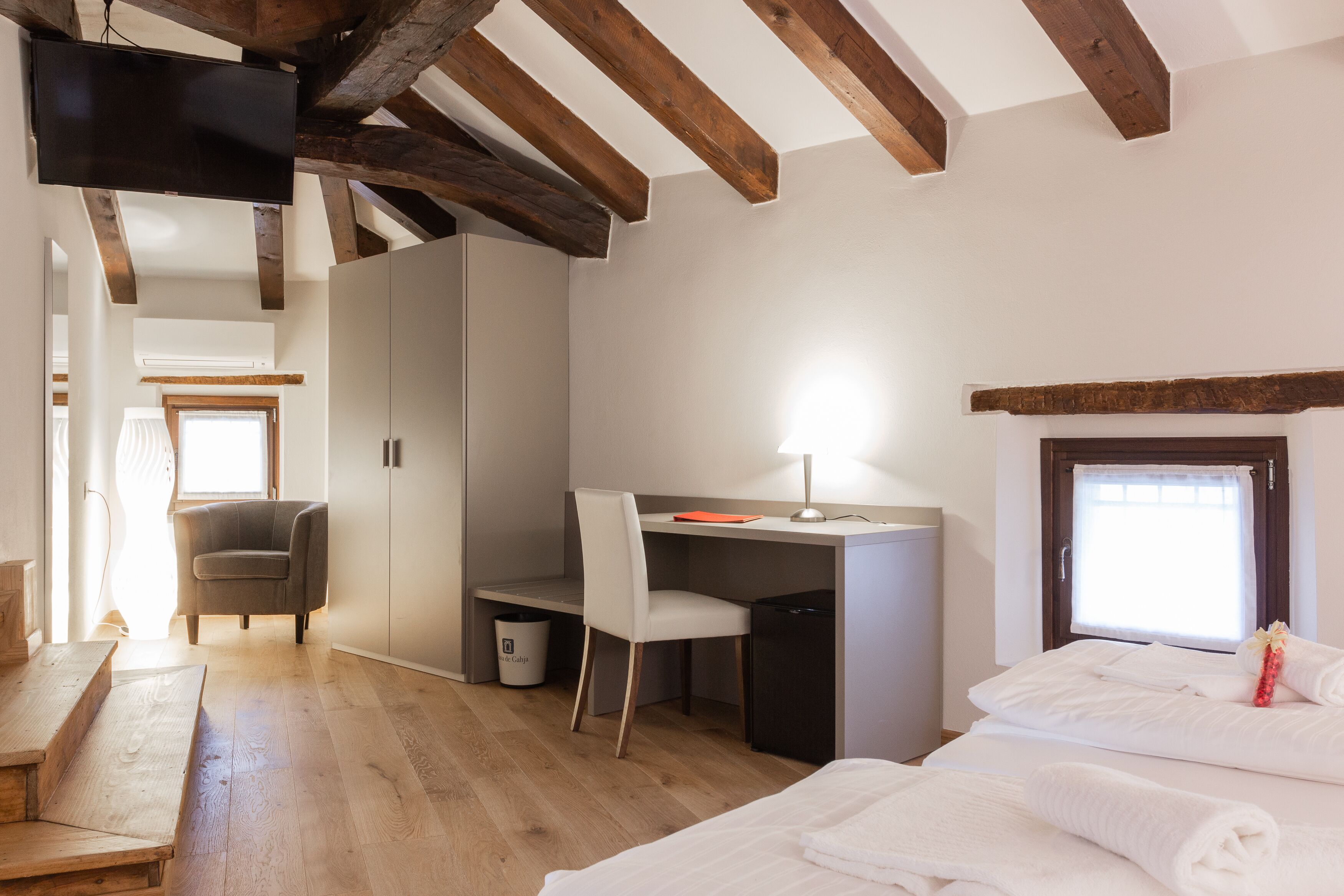 Un dormitorio con cama, escritorio, silla y ventana.