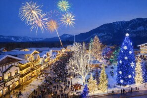 A snowy village with illuminated buildings and a large decorated Christmas tree. - Log Cabin Life| Hot Tub | Pool Table | BBQ | Deck (Leavenworth)
