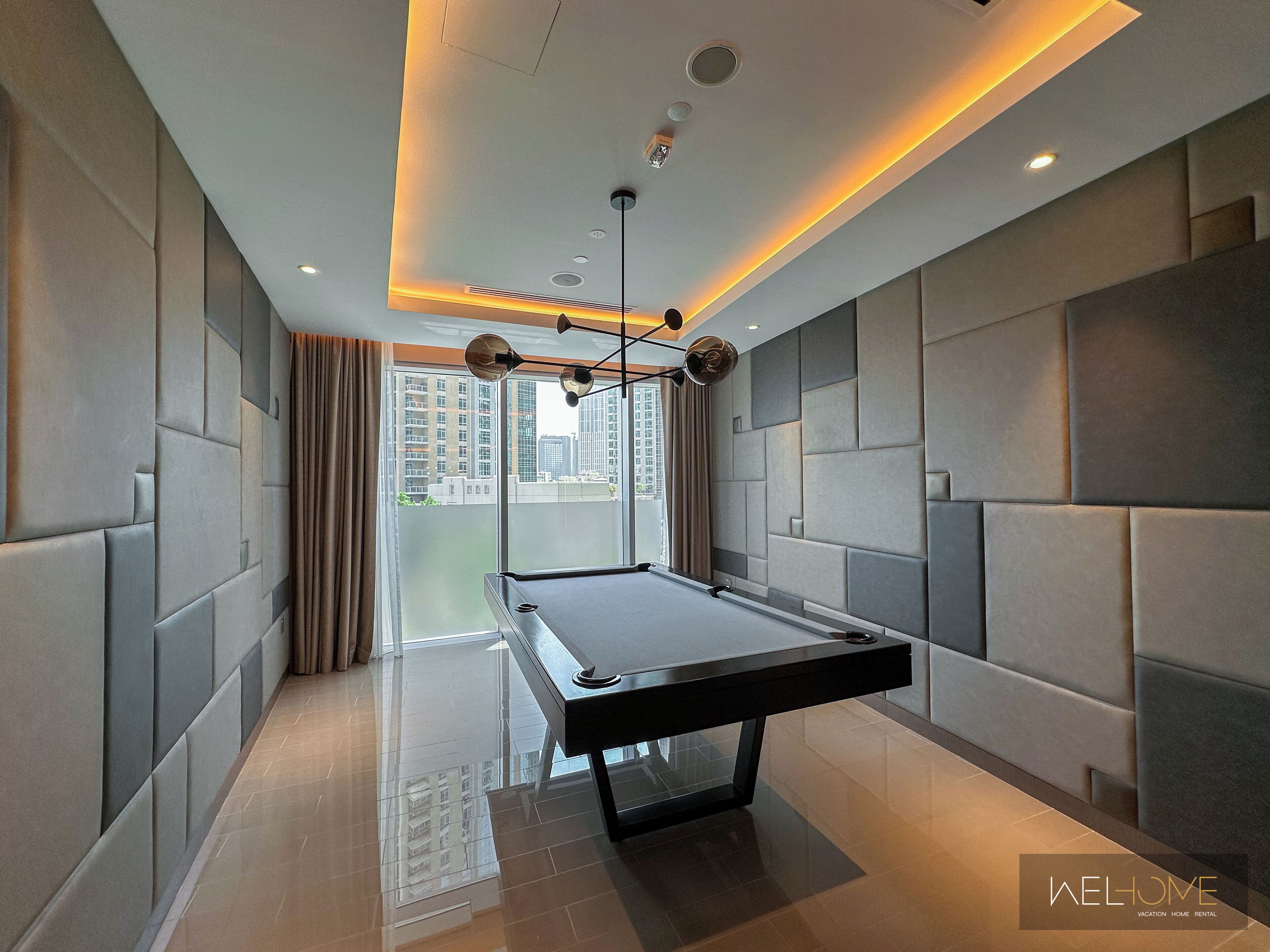A modern room with a pool table, large windows, and a city view.