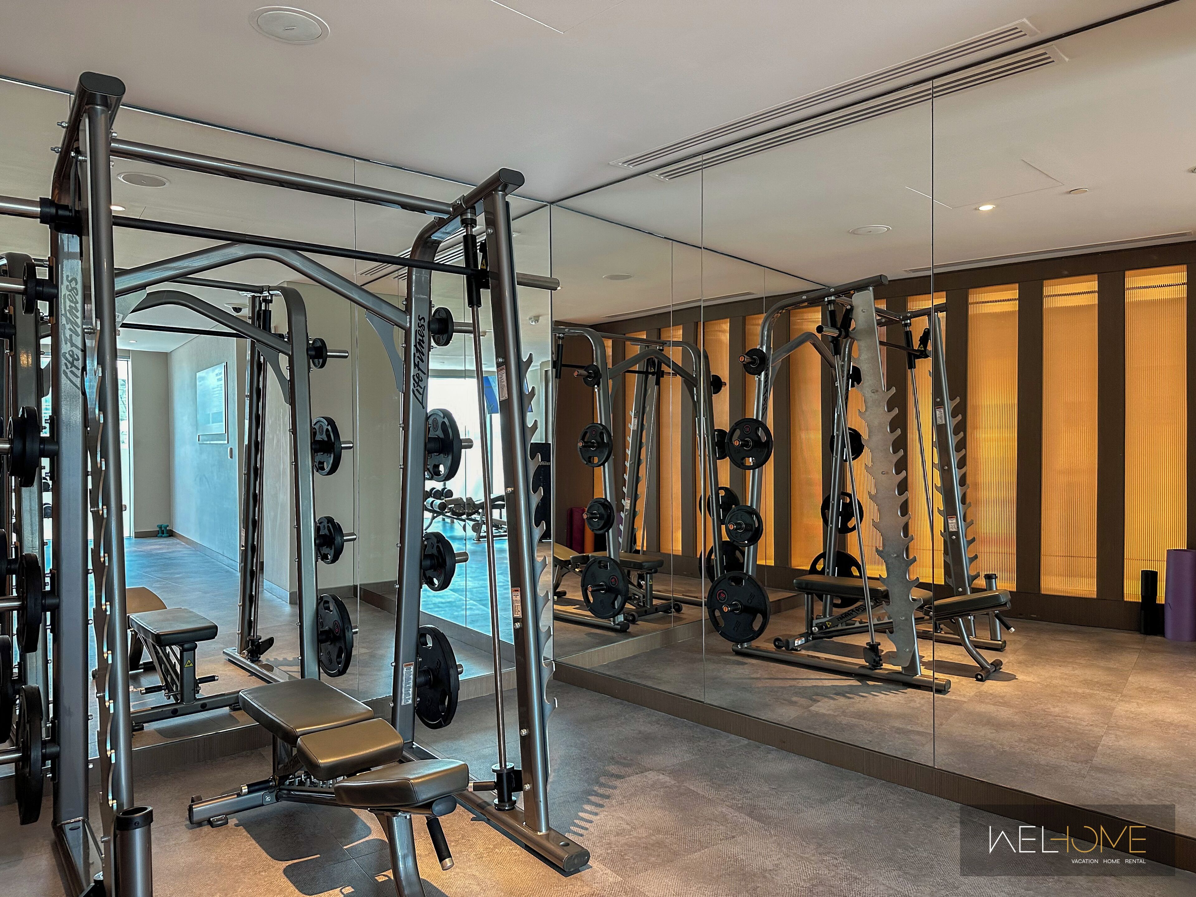 Une salle de sport moderne équipée de divers appareils de musculation, notamment des supports à squats et des bancs.