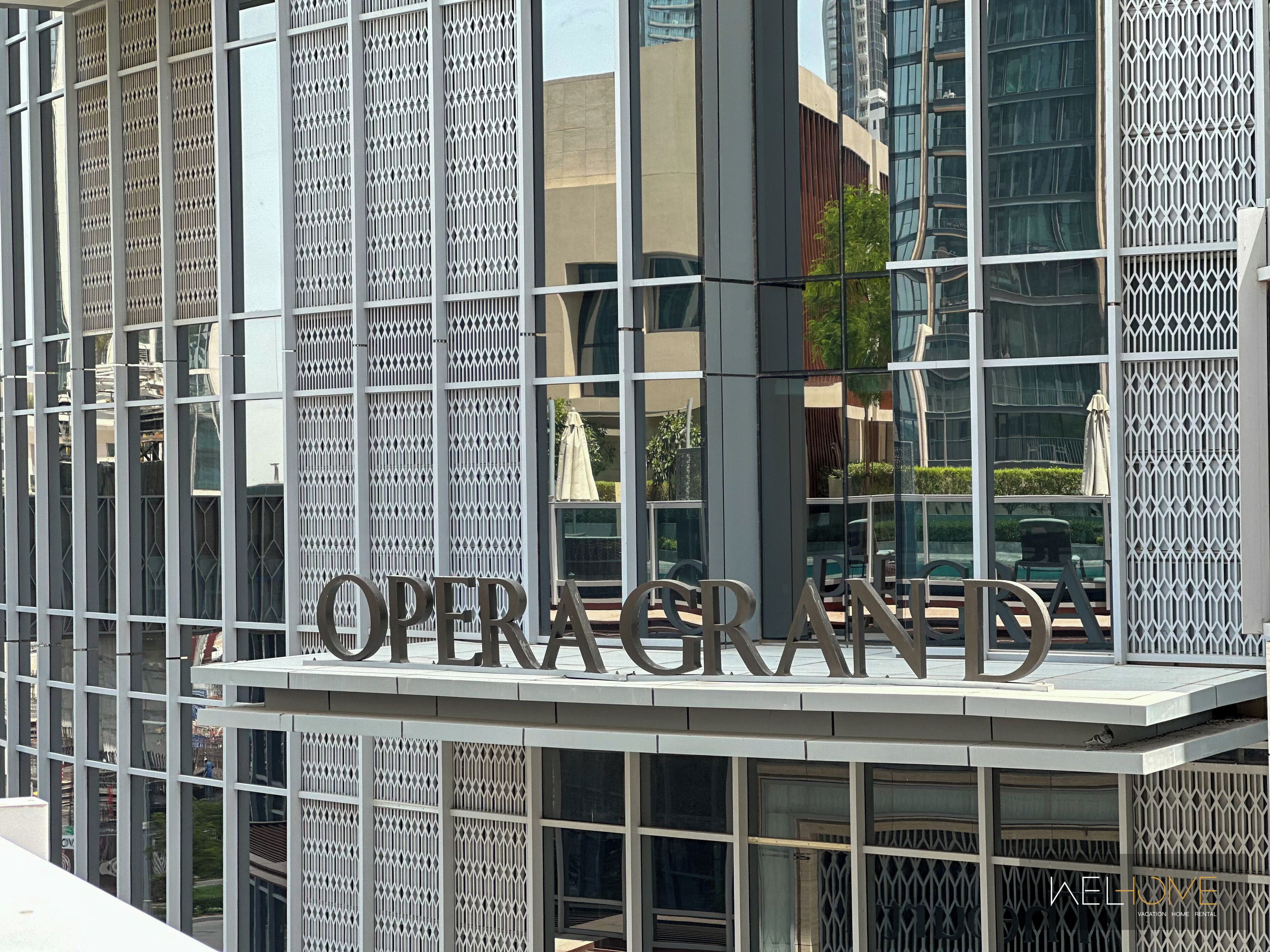 Fachada de edificio con un cartel que dice 'OPERA GRAND' y un letrero de 'BIENVENIDOS' debajo.