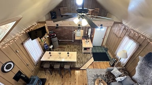Un espace compact aménagé sous les combles, comprenant une cuisine, un coin repas et un espace salon.