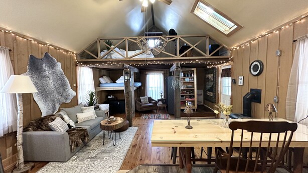 Un espace de vie chaleureux de style loft, doté d’un haut plafond, de poutres en bois, d’un coin repas et d’un lit en mezzanine.