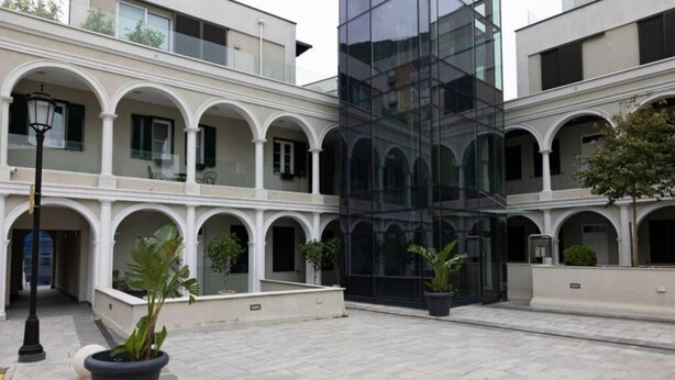 A courtyard with a modern glass building, arched walkways, and potted plants. - Charming Colonial Flat in historic building (Castle Road)