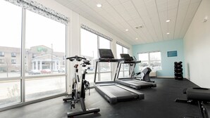 Un gimnasio con cintas de correr, elípticas y mancuernas.