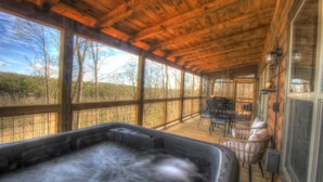A wooden deck with a hot tub, outdoor furniture, and large windows overlooking a natural landscape. - Starway to Heaven Cabin at Red River Gorge  - Hot Tub - Great View (Frenchburg)
