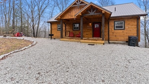 A log cabin with a porch, a red door, and a gravel driveway. - Starway to Heaven Cabin at Red River Gorge  - Hot Tub - Great View (Frenchburg)