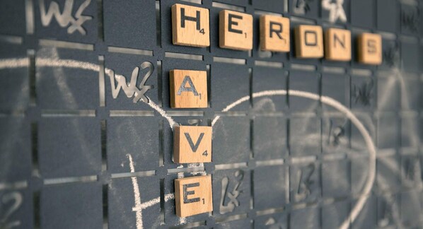 Un tablero de Scrabble con la palabra 'HERON' escrita.